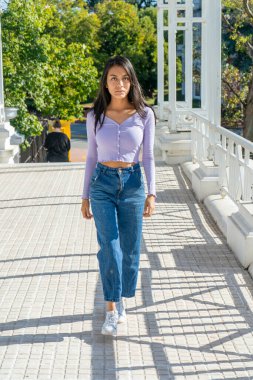 İleriye bakan genç bir kadın, eski bir köprüde yürüyor..