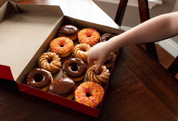 Child Hand Reaching Box Assorted Donuts Table — Stock Photo, Image