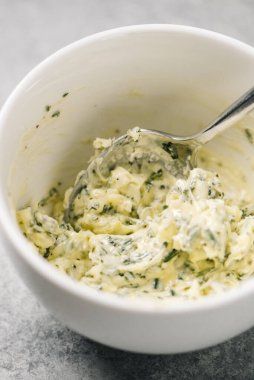 Mixed herb butter mixed in a bowl with a spoon clipart