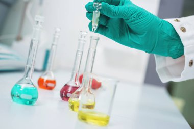 Test tüpleri yakın çekim yapan bir kimya laboratuarı çalışanının elleri..