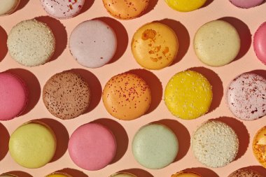 Pembemsi arka planda renkli Fransız kurabiyelerinin üst görüntüsü, yemek deseni. Badem unlu popüler krema bazlı şekerleme.