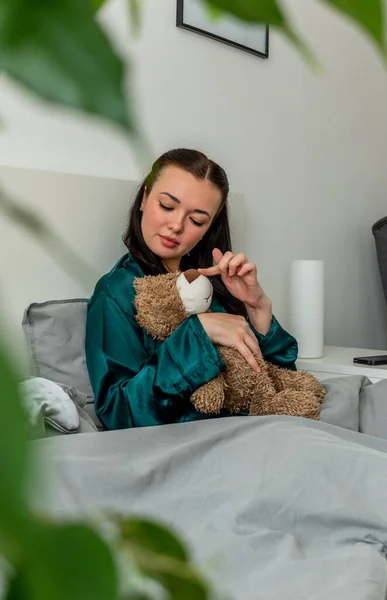 Jonge Vrouw Zijden Pyjama Zit Het Bed Knuffelt Een Teddybeer — Stockfoto