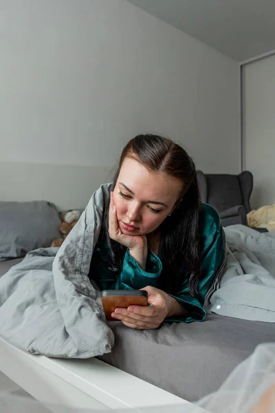 Mladá Žena Hedvábné Pyžamo Ležící Posteli Drží Telefon Ruce Práce — Stock fotografie