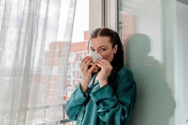 Jonge Vrouw Drinkt Koffie Uit Mok Terwijl Bij Het Raam — Stockfoto