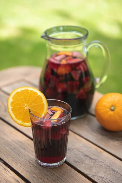 A glass of red sangria with a pitcher