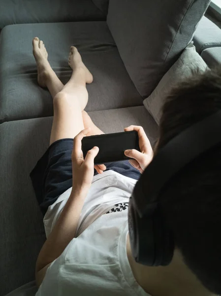 Boy 13-15 years old on the couch with a smartphone in his hands