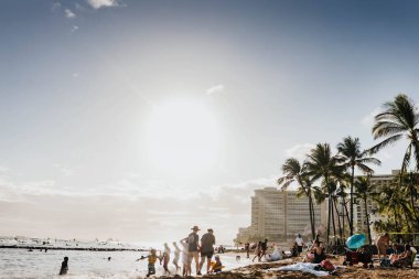 İnsanlar Waikiki 'de güneşli bir günde sahilde eğleniyorlar.