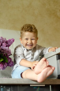 Çocuk 2 yaşında, bir buket leylağın yanında gülümsüyor.