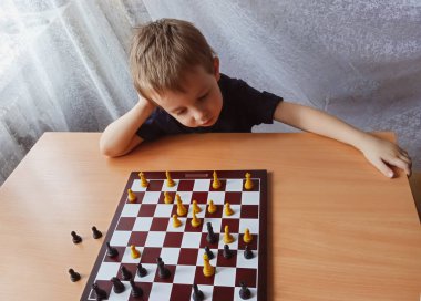 Küçük çocuk evde satranç oynarken düşünür. Boş zaman
