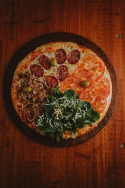 Dört sezonluk pizza, domates, salam, soğan ve roka.