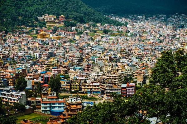 Colourful cityscape infrastructure housing of Kathmandu against mountains in Nepal during early morning light.