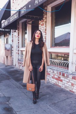 Restoranın önündeki kaldırımda telefonunu tutan kadın..