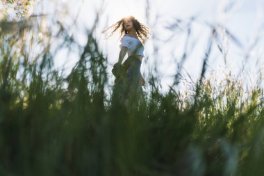 Güneşe karşı buğday tarlasında şapkalı bir kadın.