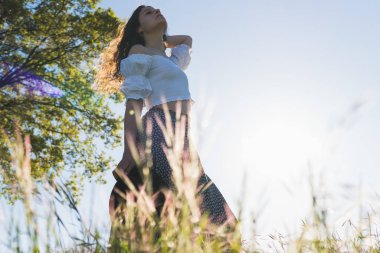 Güneşe karşı buğday tarlasında şapkalı bir kadın.