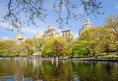 İlkbahar taze yeşillik dalgalı göl suyuna yansıyan insanlar Central Park 'ta rıhtımda geziniyor.