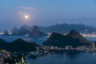 Okyanus, dağlar ve gökyüzünde parlak dolunay ile güzel bir mavi saat gün doğumu, Rio de Janeiro, Brezilya