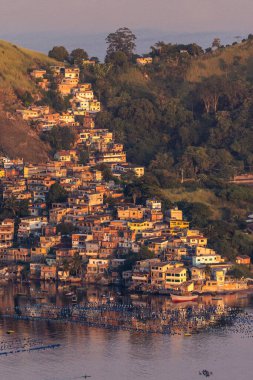 Brezilya, Rio de Janeiro 'da okyanus kıyısındaki varoşlara ve balıkçıların şamandıralarına güzel bir gün doğumu manzarası