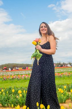 Lale çiftliğinin yanında genç ve mutlu bir kadının portresi.