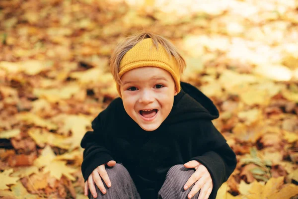 可爱的孩子 5岁的男孩 穿着黑色的帽衫 戴着黄色的王冠 在秋天的街上玩得很开心 在落叶的地毯上跳着跑着 — 图库照片