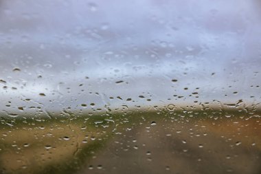Yağmur ön camdan kırsal manzarayı karartıyor