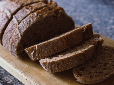 Tahta kesme tahtasına dilimlenmiş tam buğday ekmeği.