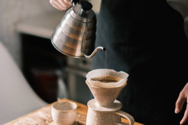 Mutfakta pourover kahvesi yapmak, filtre damlasına sıcak su dökmek.