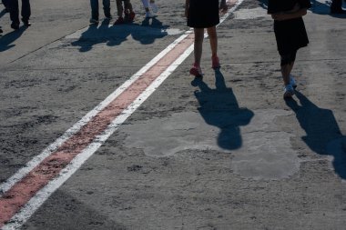 Beton bir arka planda yürüyen insanların ayakları