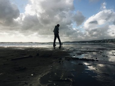 Yalnız bir çocuk deniz sahilinde yürüyor.