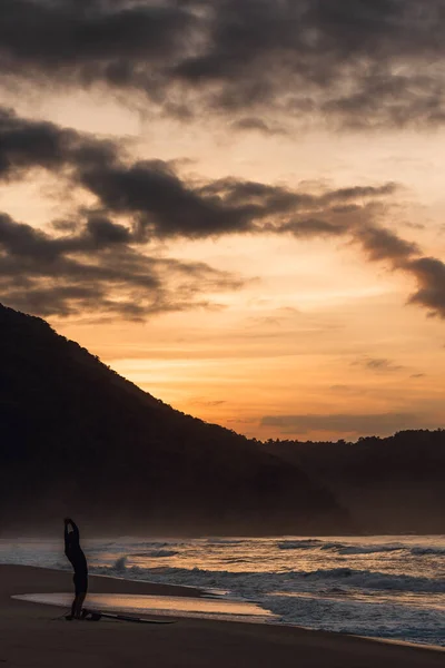 Muž Protahuje Jeho Surfovací Prkno Břehu Při Východu Slunce — Stock fotografie