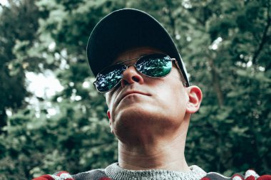 Güneş gözlüklü ve şapkalı bir adam selfie çekiyor.