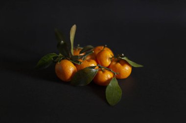 Koyu arkaplanda bir grup mandalina.