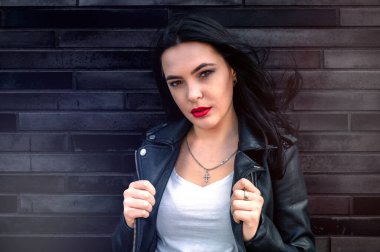 Bir binanın arka planında genç bir kadının portresi.