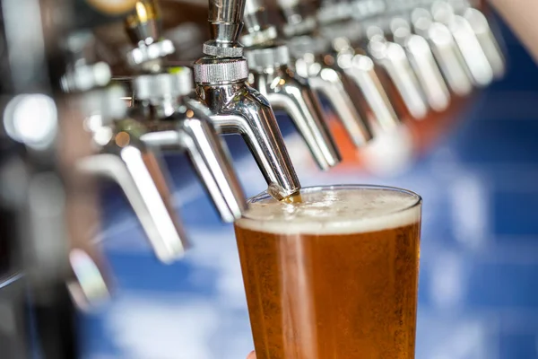 Cerveja Linha Torneiras Enchimento Vidro Contra Fundo Azul — Fotografia de Stock