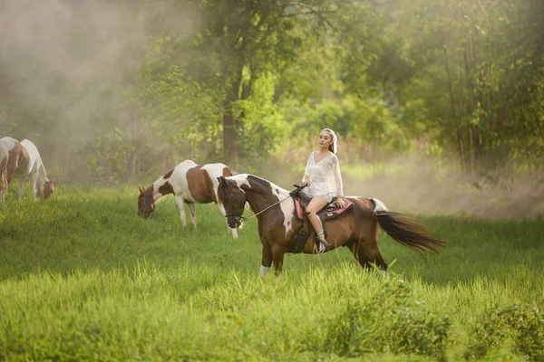 美しいアジアの女性が農場で馬を狩る — ストック写真