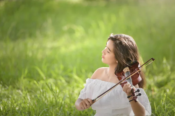 放松年轻女子在草原上拉小提琴 — 图库照片
