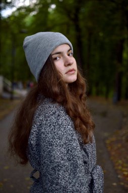 Parkta yürüyen ve kameraya bakan bir kızın portresi..