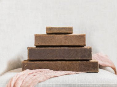 Pembe keten üzerine istiflenmiş dört kahverengi deri fotoğraf kitabı.