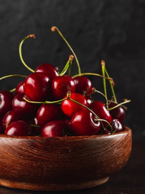 Koyu arkaplanda kiraz. Taş tabakta taze kiraz.