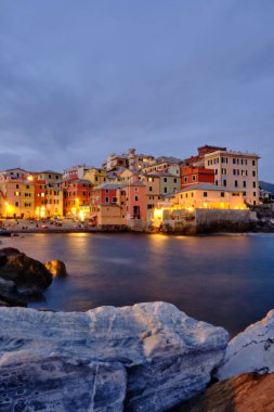 Boccadasse sahilinin renkli evleri ve arkasında yumuşak dalgalar olan uzun pozlu bir fotoğrafı. Cenova, Ligurie, İtalya