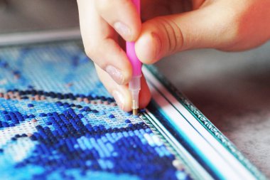 Genç bir kız elmas mozaik koleksiyonu yapıyor.