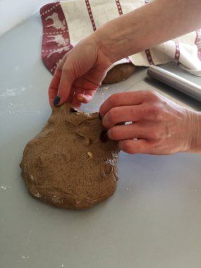 Bir kadın mutfak masasında çavdar hamuru yoğuruyor.