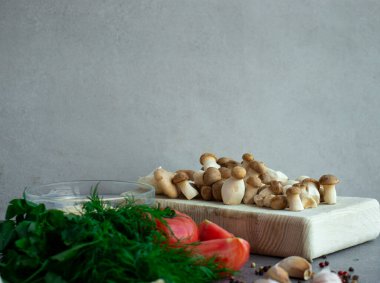 Gri arka planda küçük mantarlar, domatesler, sos ve baharatlar