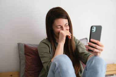 Young woman at home having video call with friends and laughing.