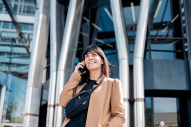 İş kadını telefon kullanıyor ve gülümsüyor.