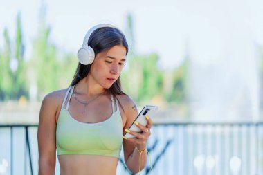 Sportif kadın spor yapmadan önce akıllı telefonuna danışıyor.