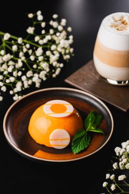 Siyah arka planda havuç kremalı tatlı ve kahve.