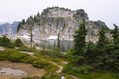 Pct boyunca ağaçlar ve granit kayalarla çevrili Alp Gölü.