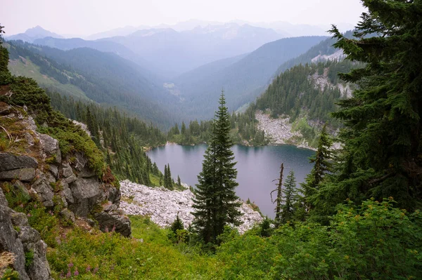 Pct boyunca ağaçlar ve granit kayalarla çevrili Alp Gölü.