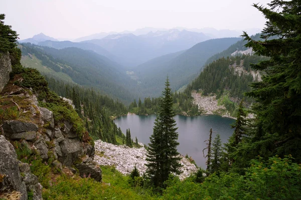Pct boyunca ağaçlar ve granit kayalarla çevrili Alp Gölü.