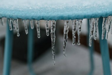 Mavi bir masadan sarkan küçük buz saçakları